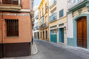 A narrow street lined with colorful buildings, including a building with a sign reading 'PERE LUIS MARIA LLOP.'