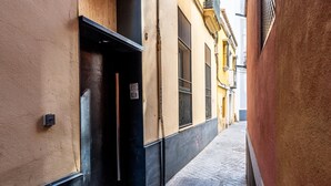 A narrow alleyway with buildings on either side, a door on the left, and a metal grate on the ground.