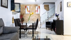 A modern living room with a dining area, a staircase, and a black bookshelf.