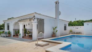 A white building with a swimming pool, a covered patio, and potted plants. - Holiday Home 'Castro' with Mountain View, Wi-Fi and Air Conditioning (Vejer de la Frontera)