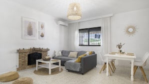 A living room with a fireplace, sofa, dining table, and decorative wall art. - Holiday Home 'Castro' with Mountain View, Wi-Fi and Air Conditioning (Vejer de la Frontera)