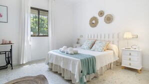 A bedroom with a bed, bedside tables, a nightstand, a window with curtains, and wall decorations. - Holiday Home 'Castro' with Mountain View, Wi-Fi and Air Conditioning (Vejer de la Frontera)