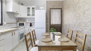 A kitchen with white cabinets, a microwave, and a refrigerator. There is a dining table with four chairs and a potted plant. - Holiday Home 'Castro' with Mountain View, Wi-Fi and Air Conditioning (Vejer de la Frontera)