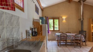 Eine Küche mit Spüle, Kaffeemaschine, Kühlschrank und einem Esstisch mit Stühlen.