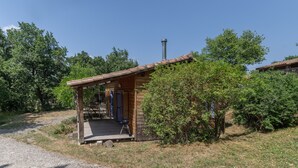 Eine kleine Holzhütte mit einer Veranda, umgeben von Bäumen und blauem Himmel.