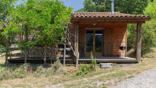 Eine Holzhütte mit Ziegeldach, einer Veranda und einem Schornstein.
