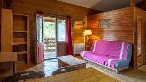 Interior de uma cabana de madeira com um sofá, uma mesa e uma cadeira.