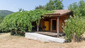 Een houten hut met een overdekte veranda, een deur en een kleine buitenbarbecue.