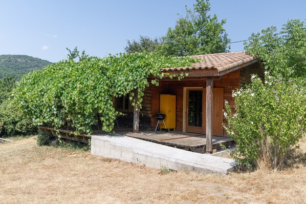 A wooden cabin with a covered porch, a door, and a small outdoor grill.