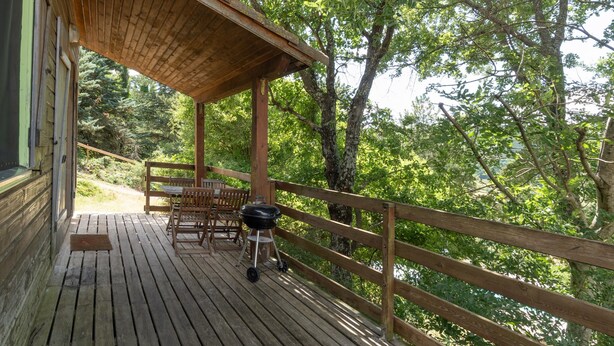 A wooden deck with outdoor seating and a grill.