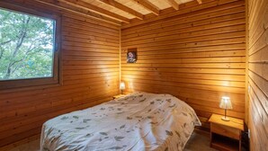A wooden-paneled room with a bed, a nightstand, a lamp, and a framed picture on the wall.