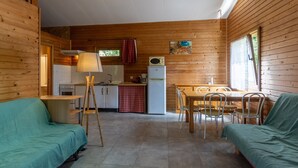 A cozy cabin with a kitchenette, dining area, and two green-covered couches.