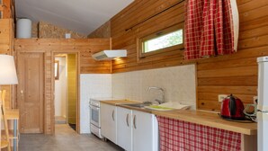 A kitchen with wooden walls, a window, a sink, and a stove.