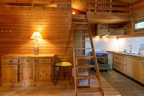 A wooden interior with a kitchen, a dining area, and a staircase.