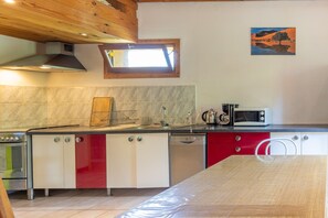 A kitchen with a stove, microwave, and red cabinets.