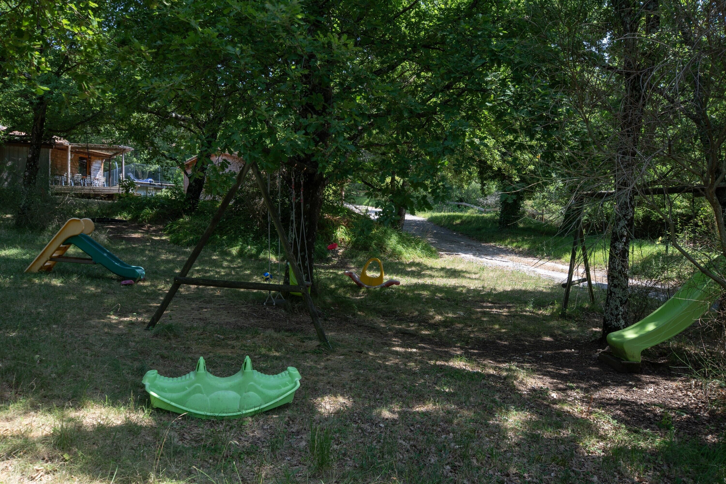 A playground with slides and swings surrounded by trees.
