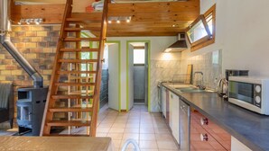 Una cocina con una escalera de madera, una estufa y un microondas.