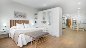 A modern bedroom with a bed, bedside tables, a bench, a wardrobe, and a kitchenette. - 'Suite 1 San Agustin' with Wi-Fi (Icod de los Vinos)