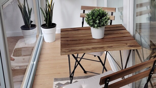 A balcony with a wooden table and chairs, potted plants, and a view of buildings. - 'Suite 1 San Agustin' with Wi-Fi (Icod de los Vinos)