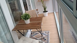 A modern balcony with a wooden table and chairs, potted plants, and a view of the cityscape. - 'Suite 1 San Agustin' with Wi-Fi (Icod de los Vinos)
