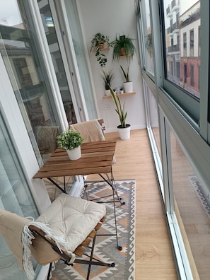 Ein modernes Loft-Zimmer mit Esstisch aus Holz, einer gepolsterten Bank und Pflanzen in Töpfen auf Regalen.