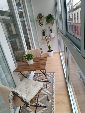 Ein modernes Loft-Zimmer mit Esstisch aus Holz, einer gepolsterten Bank und Pflanzen in Töpfen auf Regalen.