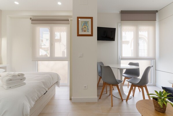 A modern bedroom with a bed, a desk, and a TV.