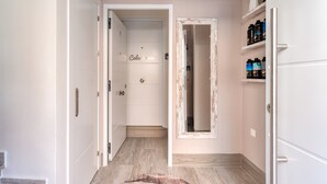 A hallway with a door labeled 'Calceena,' a mirror, and a shelf with bottles.