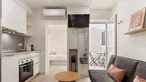 A modern apartment with a kitchenette, a sofa, a TV, and a dining area. - La Cala Home - Cala Arena - Ground Floor Studio with Private Patio and Pool (La Cala de Mijas)