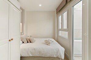 A bedroom with a bed, pillows, a window, and a door.