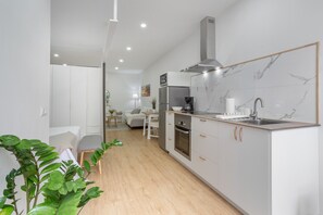 A modern kitchen with white cabinets, a built-in oven, and a stainless steel sink.