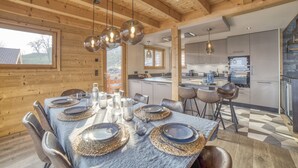 Una cocina moderna con electrodomésticos de acero inoxidable, una zona de comedor con una mesa de mármol y vigas de madera en el techo.