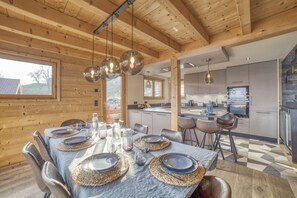 Una cocina moderna con electrodomésticos de acero inoxidable, una zona de comedor con una mesa de mármol y vigas de madera en el techo.