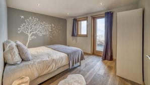 Un dormitorio con cama, un mural en la pared, una ventana con cortinas y una puerta.