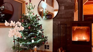 Una habitación acogedora con un árbol de Navidad, una chimenea y un espejo redondo.