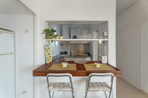 Une cuisine avec un plan de travail en bois, deux chaises, un four à micro-ondes et un évier.