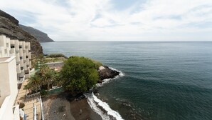 A coastal hotel with a beach, rocky shoreline, and ocean views.