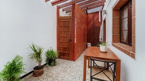 A covered patio with a wooden table and chairs, potted plants, and a wooden door. - Vacation Home 'Olas De Plata' with Sea View, Private Pool and Wi-Fi (Playa del Hombre)