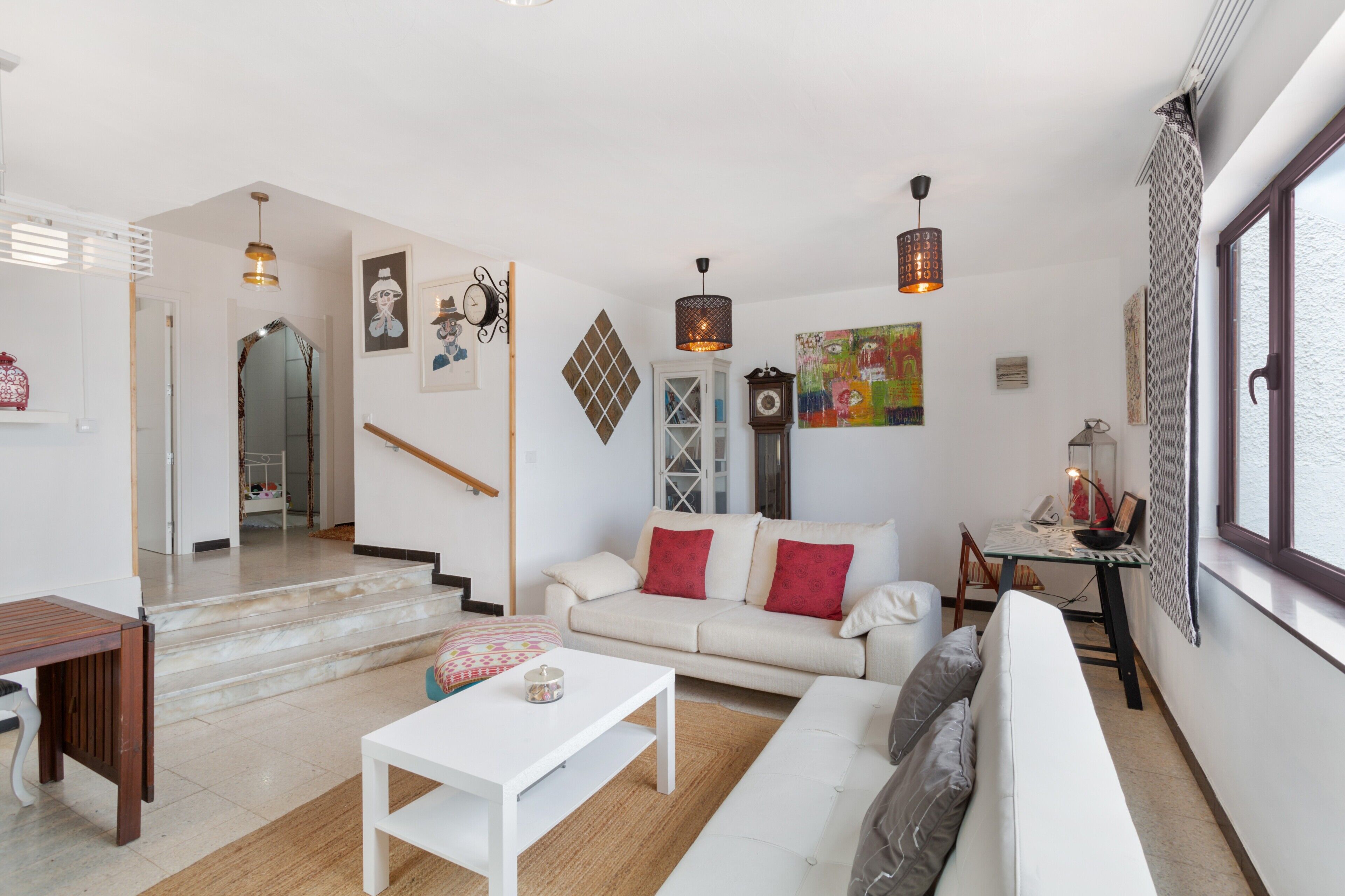 Una sala de estar moderna con un sofá blanco, una mesa de centro y un comedor con mesa y sillas.