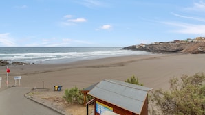 A beach with a wooden structure, a flag, and a signboard. - Vacation Home 'Olas De Plata' with Sea View, Private Pool and Wi-Fi (Playa del Hombre)