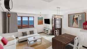 A modern living room with a white sofa, a coffee table, a wooden dining table, and a TV. - Vacation Home 'Olas De Plata' with Sea View, Private Pool and Wi-Fi (Playa del Hombre)