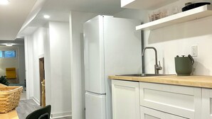 Une cuisine moderne avec des meubles blancs, un four encastré et un plan de travail en bois.