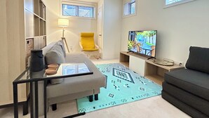 Un salon moderne avec un canapé, un fauteuil jaune, un téléviseur et un tapis à motifs.