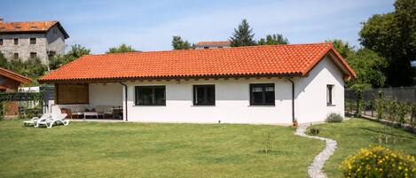 A single-story house with a red-tiled roof, a small front yard, and a pathway leading to the entrance.
