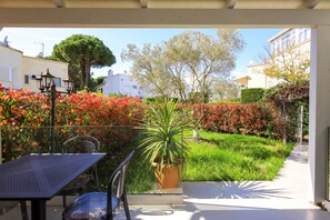 An outdoor patio area with a table and chairs, surrounded by a hedge of red flowers and a potted plant. - Lura Villa 001 in Durr s (Ishëm)