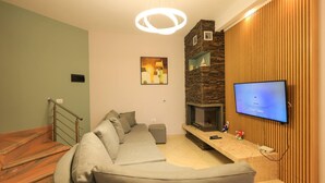 Un salon moderne avec un canapé d’angle, une cheminée, un téléviseur et un escalier.