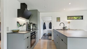 A modern kitchen with grey cabinetry, a built-in oven, and a large island with a sink. - Cottage with fjord view in lovely Vellerup (Skibby)