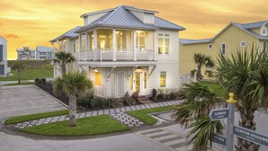 A two-story house with a balcony, a driveway, and a well-maintained lawn. - SBS700 Shared Resort Style Pools, Boardwalk to the Beach, Charcoal Grill (Port Aransas)