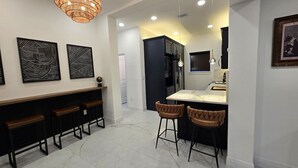 Una cucina moderna con isola centrale, sgabelli da bar e illuminazione a sospensione.