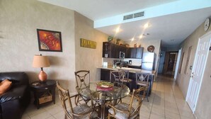 Una sala de estar con comedor, cocina y una puerta que da a otra habitación.